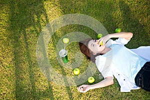 Young women lying in summer grass with eat apple