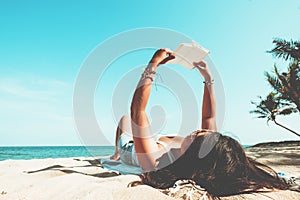 Young women lying on a tropical beach, relax with book