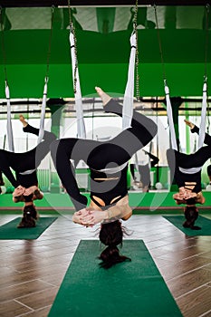 Young women making antigravity yoga exercises with a group of people. aero fly fitness trainer workout. white hammocks.