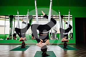 Young women making antigravity yoga exercises with a group of people. aero fly fitness trainer workout. white hammocks.