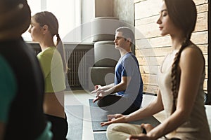 Young women and man in yoga class, relax meditation pose