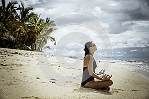 Young women meditating on the pristine tropical beach