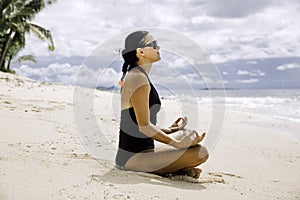 Young women meditating on the pristine tropical beach