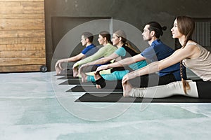 Young women and men in yoga class, doing stretching exercises