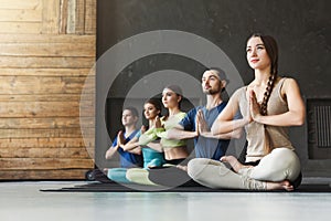 Young women and men in yoga class, relax meditation pose