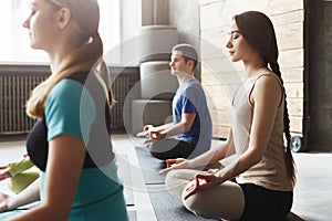 Young women and men in yoga class, relax meditation pose