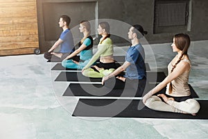 Young women and men in yoga class, relax meditation pose