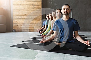 Young women and men in yoga class, relax meditation pose