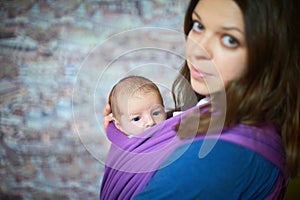 Young woman with newborn infant baby in a sling