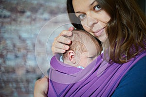 Young woman with newborn infant baby in a sling