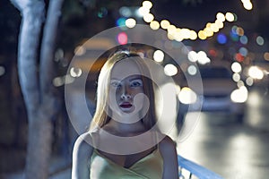 Young women in night street. Defocused carlights.