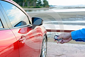 Young women opening his red car door with the control remote key