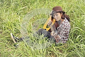 Young women playing acoustic guitar outdoor in green park. Woman person playing acoustic guitar music instrument at home, young