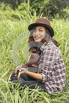 Young women playing acoustic guitar outdoor in green park. Woman person playing acoustic guitar music instrument at home, young