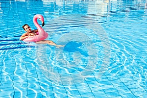 Young women pool. Happy young sexy girl in bikini swimsuit with pink inflatable flamingo float in blue water. Travel