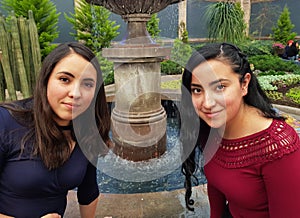 young women posing in a park fountain