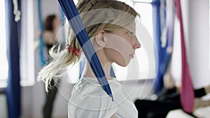 Young women practice aero gravity yoga in studio.