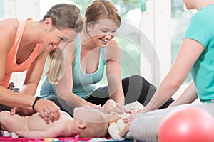 Young women practicing how to wrap children in mother-child less