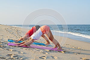 Young women practicing yoga on the beach