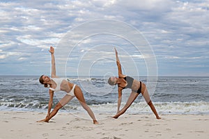 Young women practicing yoga on the beach