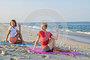 Young women practicing yoga on the beach. Beautiful girls practicing yoga