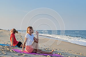 Young women practicing yoga on the beach. Beautiful girls practicing yoga