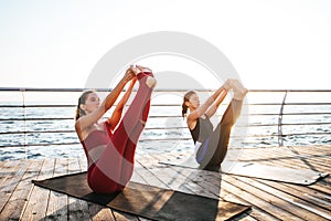 Young women practicing yoga on the seashore