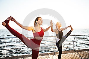 Young women practicing yoga on the seashore