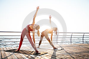 Young women practicing yoga on the seashore