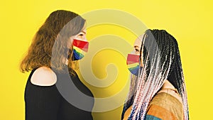 Young women in protective rainbow mask. Side view of two females standing opposite each other in mask lgbt.