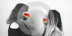 Young women in protective rainbow mask. Side view of two females standing opposite each other in mask lgbt.