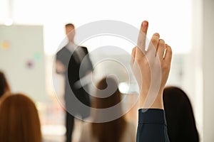 Young woman raising hand to ask question at business training, closeup photo