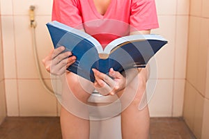 Mladý ženy čtení kniha zatímco v záchod 
