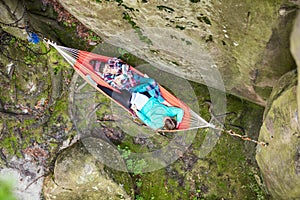 Young women reading books while relaxing in hammock near cliff