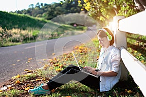 Young women relaxation listening music with notebook sitting on the grass