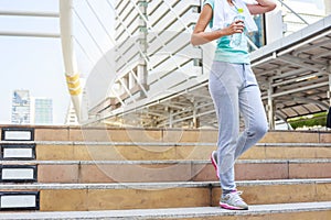 Young women resting and drinking water after jogging