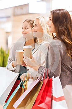 Young women with shopping bags and coffee in mall