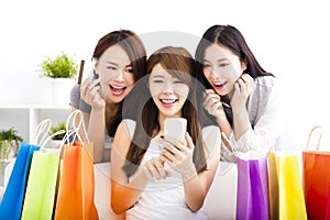 young women with shopping bags and looking at smart phone