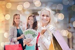 Young women with shopping bags and money in mall