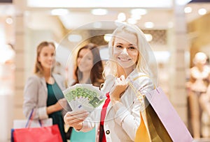 Young women with shopping bags and money in mall