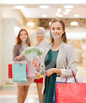 Young women with shopping bags and money in mall