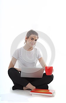 Young women is sitting on white background with laptop, cup, books and papers. Student girl studying, freelances is working.