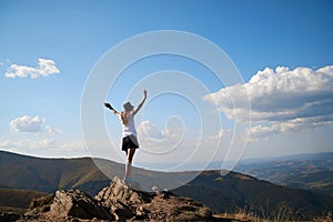 Young women standing on rock on top of the mountain. Feeling happy and free. Natural landscape in summer. Sunny rural scenery.