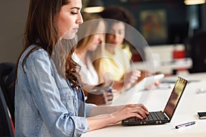 Young woman studying with laptop computer on white desk.