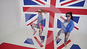 young women in sunglasses workout dance moving in studio with UK flag