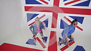 young women in sunglasses workout synchronic dancing in studio with UK flag
