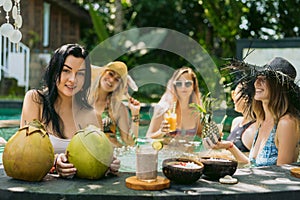 young women in swimwear drinking tropical cocktails and relaxing