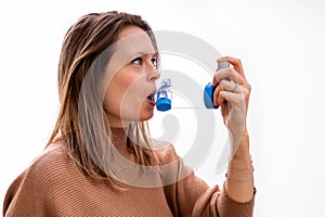 Young women taking asthma medication with an inhaler and spacer