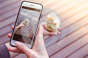 Young women is taking a picture of italian artisanal ice cream with her smartphone