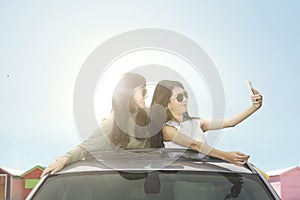 Young women taking selfie photo on car sunroof